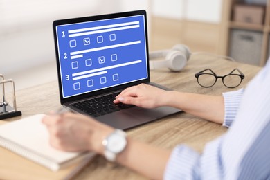 Image of Woman passing online test on laptop and writing in notebook at table, closeup