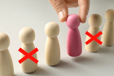 Image of Dismissal. Two human figures with red crosses among others on white table. Woman taking away another one, closeup