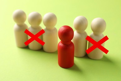 Image of Dismissal. Two human figures with red crosses among others on light green background. Red figure - boss or HR manager