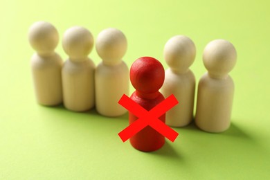 Image of Dismissal. One red human figure with cross among others on light green background