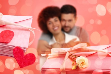 Image of Romantic couple and love letters, bokeh effect. Man hugging his beloved woman against coral background