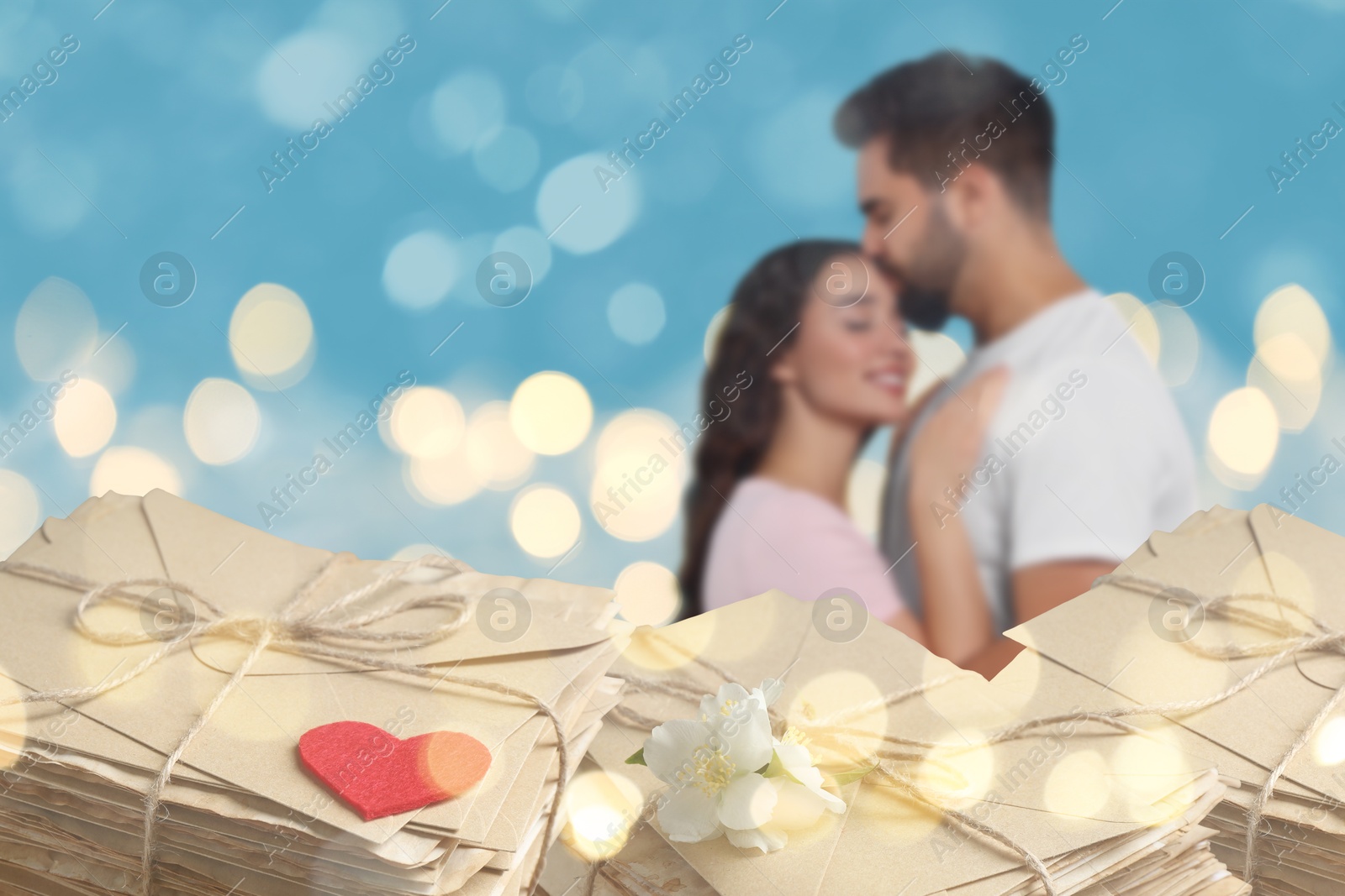 Romantic young couple and love letters, bokeh effect. Woman and man hugging against light blue background Image of Romantic young couple and love letters, bokeh effect. Woman and man hugging against light blue background