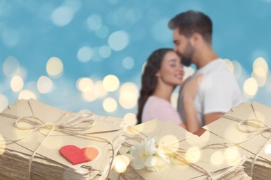 Image of Romantic young couple and love letters, bokeh effect. Woman and man hugging against light blue background
