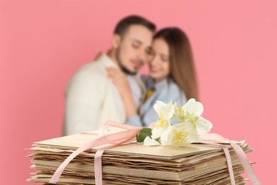 Image of Romantic young couple and stack of love letters against pink background