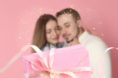 Image of Romantic young couple and love letters against pink background, bokeh effect