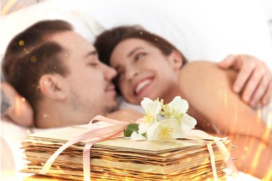 Image of Romantic young couple in bed and stack of love letters, bokeh effect