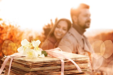 Image of Romantic couple outdoors and stack of love letters, bokeh effect. Woman hugging her beloved man
