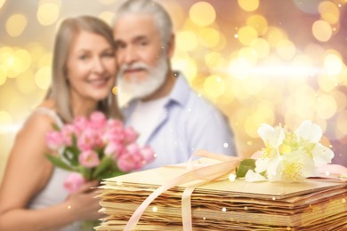 Image of Romantic senior couple and stack of love letters, bokeh effect. Woman and man with bouquet
