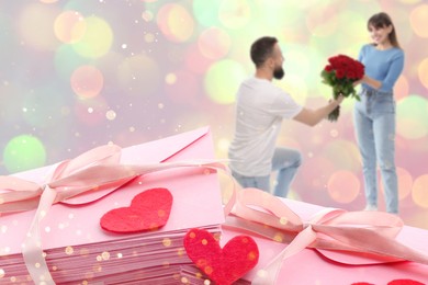 Image of Romantic young couple and love letters, bokeh effect. Man presenting bouquet to his beloved woman