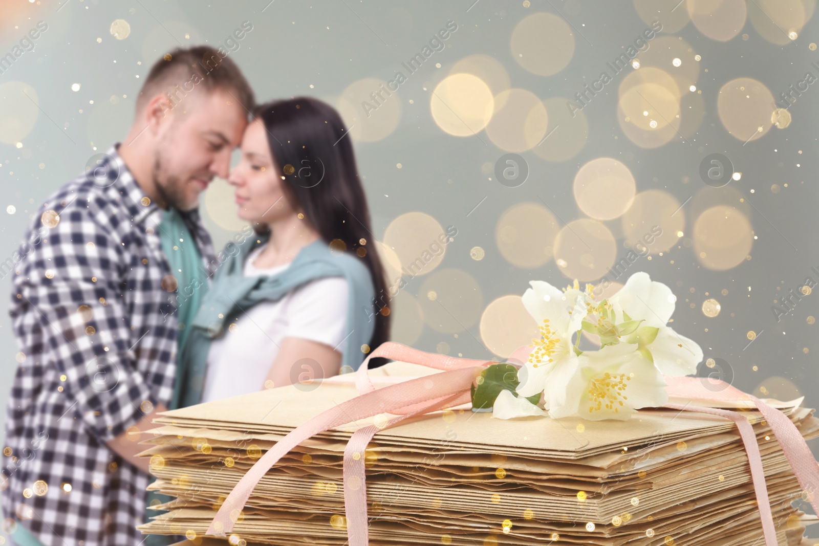 Romantic couple and stack of love letters against grey background, bokeh effect Image of Romantic couple and stack of love letters against grey background, bokeh effect