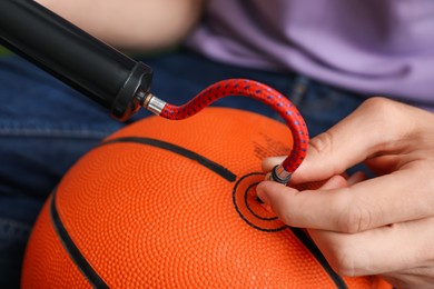 Photo of Man inflating basketball ball with manual air pump indoors, closeup