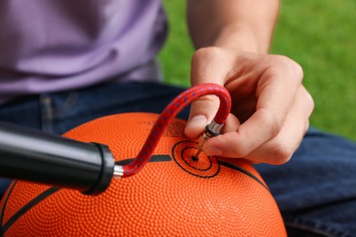 Photo of Man inflating basketball ball with manual air pump indoors, closeup