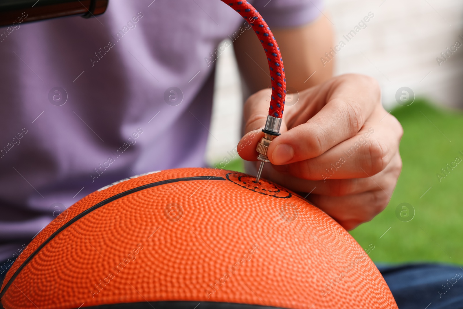 Photo of Man inflating basketball ball with manual air pump indoors, closeup