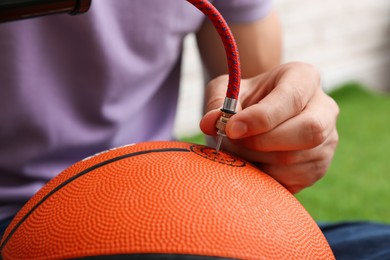 Photo of Man inflating basketball ball with manual air pump indoors, closeup