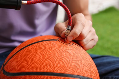 Photo of Man inflating basketball ball with manual air pump indoors, closeup