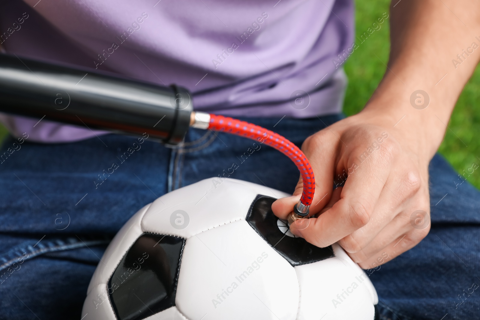 Photo of Man inflating soccer ball with manual air pump indoors, closeup