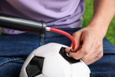 Photo of Man inflating soccer ball with manual air pump indoors, closeup