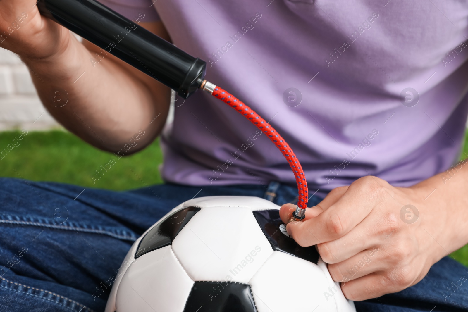 Photo of Man inflating soccer ball with manual air pump indoors, closeup