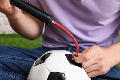Photo of Man inflating soccer ball with manual air pump indoors, closeup