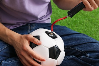 Photo of Man inflating soccer ball with manual air pump indoors, closeup