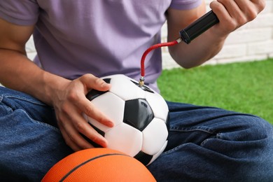 Photo of Man inflating soccer ball with manual air pump indoors, closeup
