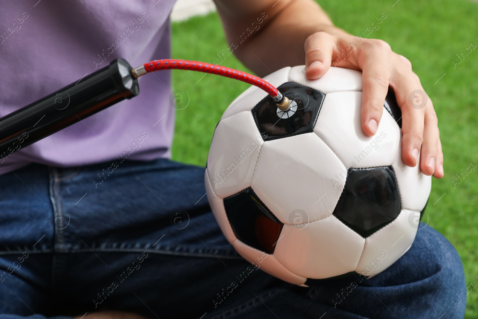 Photo of Man inflating soccer ball with manual air pump indoors, closeup