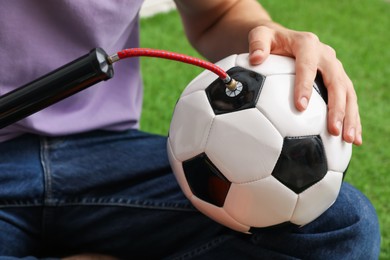 Photo of Man inflating soccer ball with manual air pump indoors, closeup