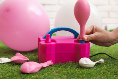 Photo of Woman inflating balloon with air pump indoors, closeup