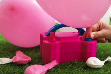 Photo of Woman inflating balloon with air pump indoors, closeup