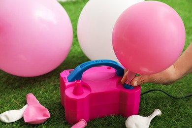 Photo of Woman inflating balloon with air pump indoors, closeup