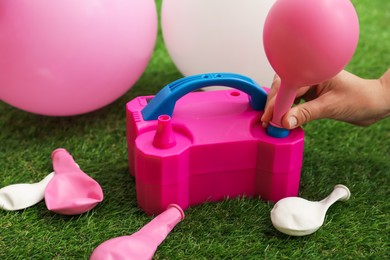 Photo of Woman inflating balloon with air pump indoors, closeup