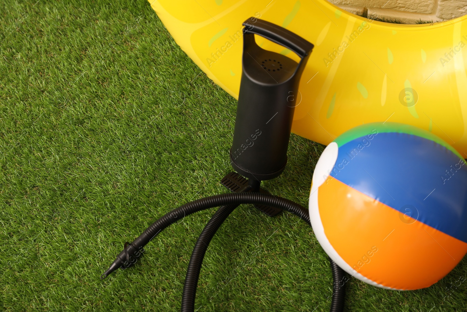 Photo of Ball, inflatable ring and manual air pump on artificial grass. Space for text