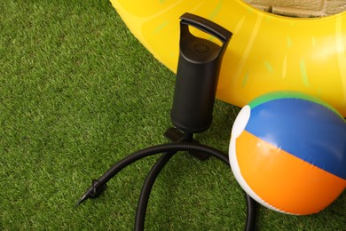 Photo of Ball, inflatable ring and manual air pump on artificial grass. Space for text