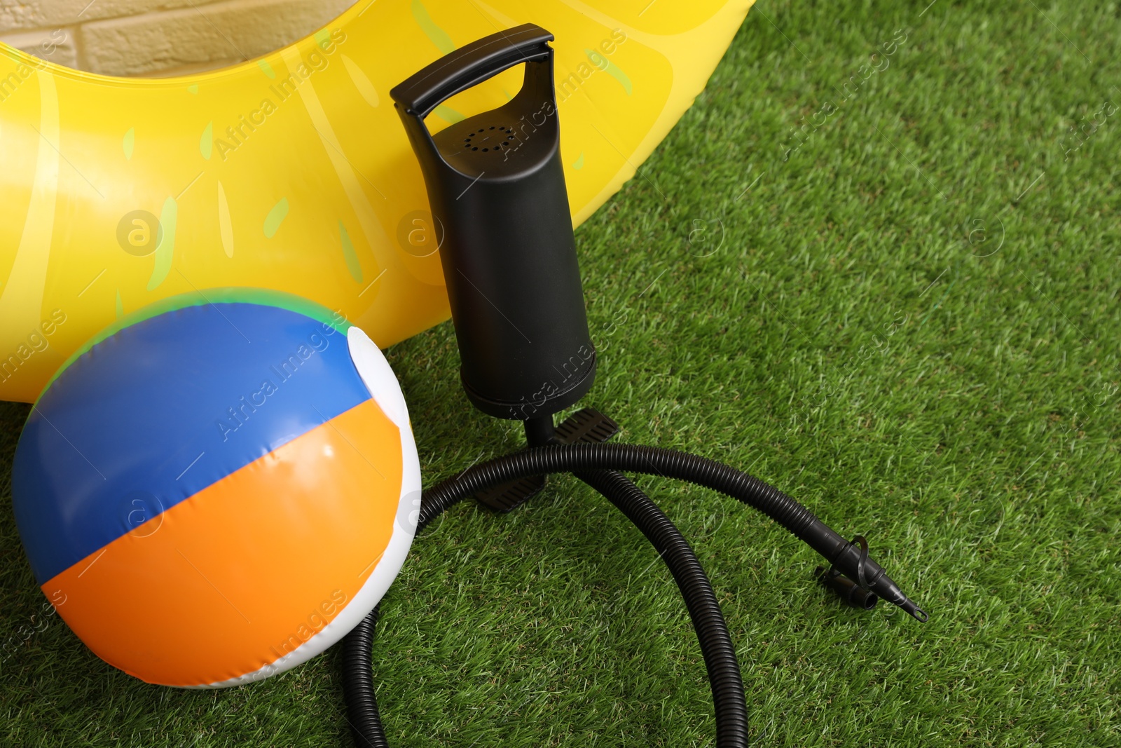Photo of Ball, inflatable ring and manual air pump on artificial grass. Space for text