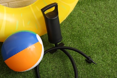 Photo of Ball, inflatable ring and manual air pump on artificial grass. Space for text