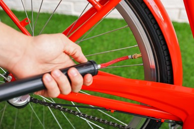 Photo of Man inflating bicycle tire with manual air pump indoors, closeup