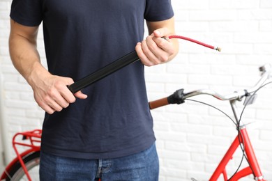 Photo of Man inflating bicycle tire with manual air pump indoors, closeup