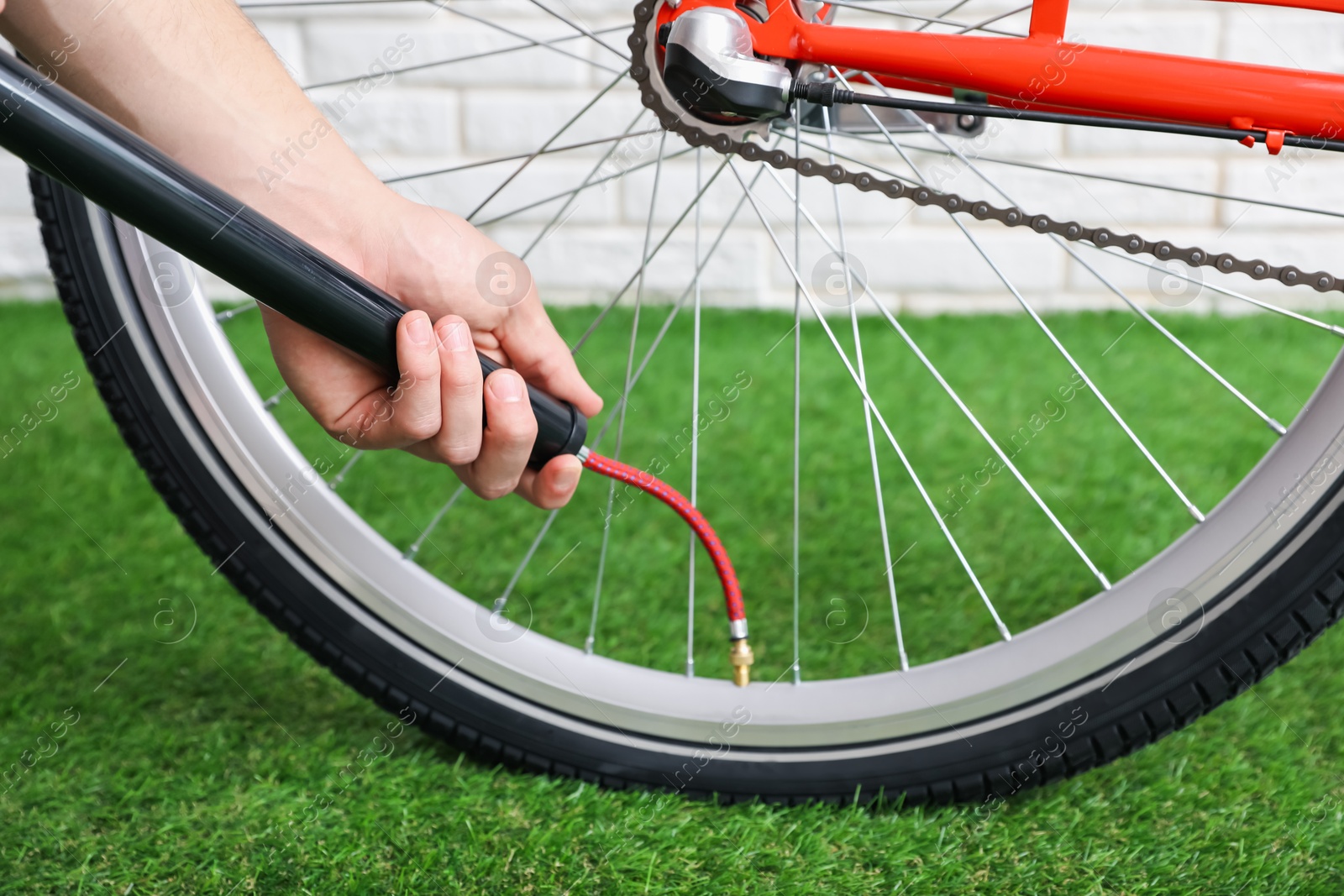 Photo of Man inflating bicycle tire with manual air pump indoors, closeup