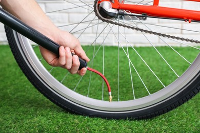Photo of Man inflating bicycle tire with manual air pump indoors, closeup