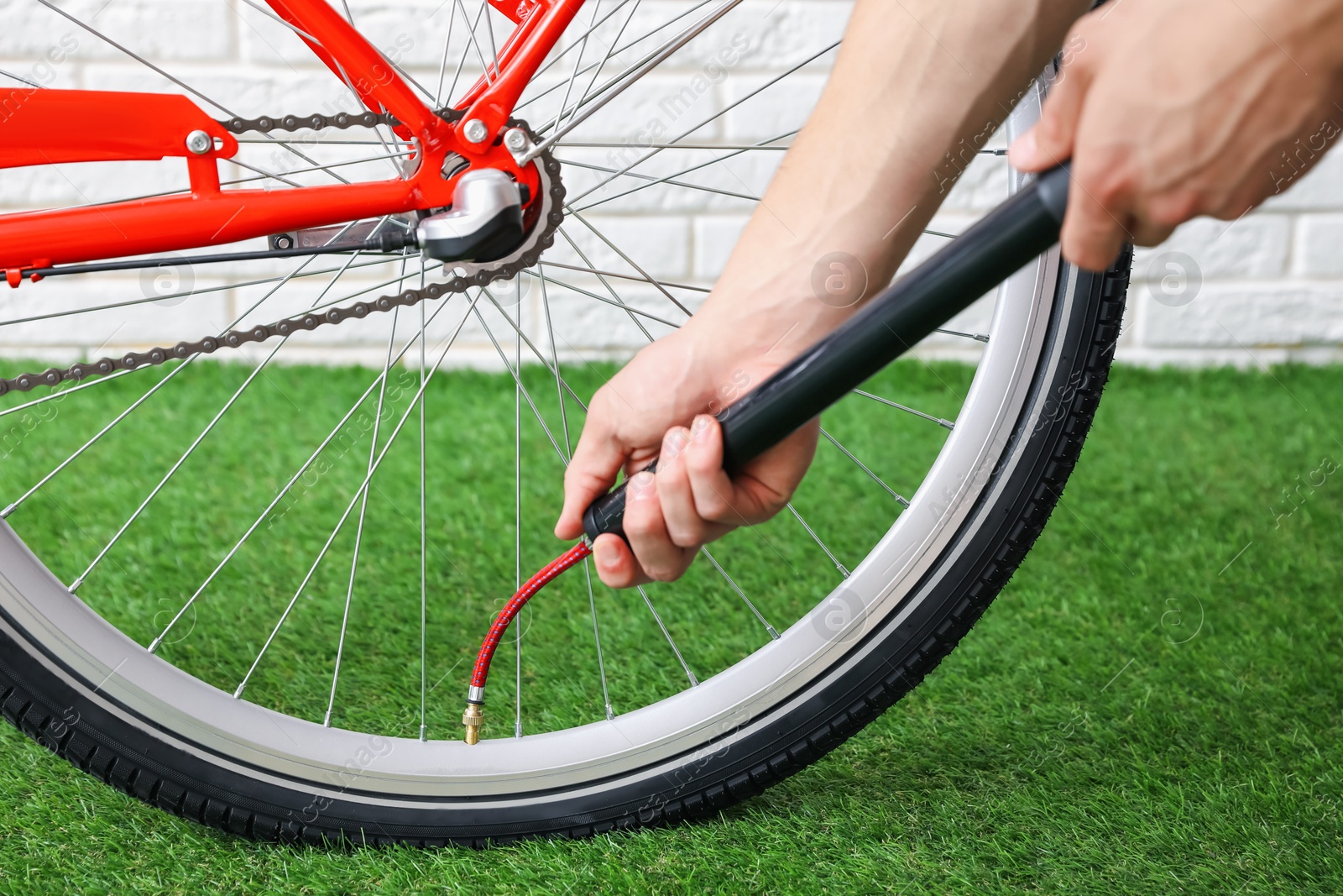 Photo of Man inflating bicycle tire with manual air pump indoors, closeup