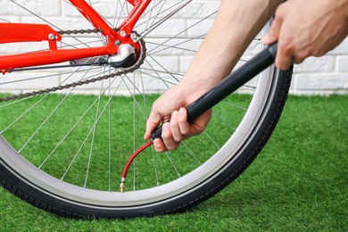 Photo of Man inflating bicycle tire with manual air pump indoors, closeup
