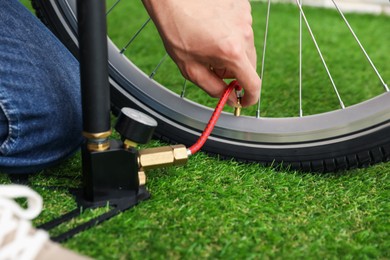 Photo of Man inflating bicycle tire with manual air pump indoors, closeup