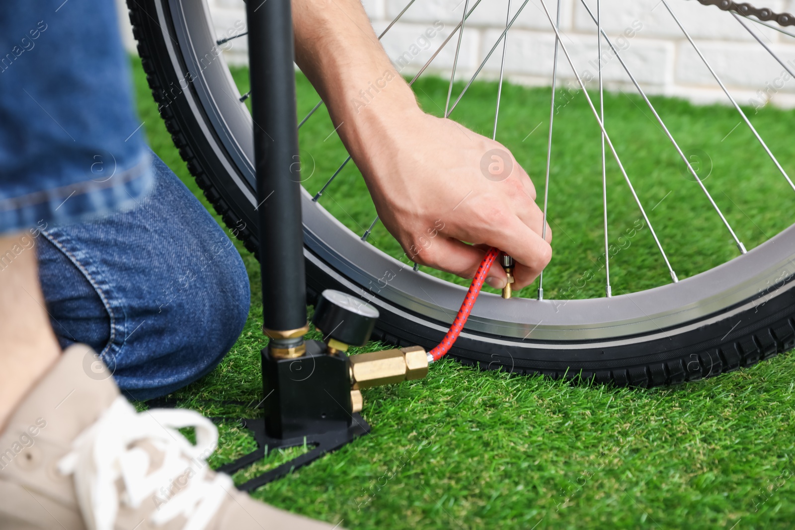 Photo of Man inflating bicycle tire with manual air pump indoors, closeup