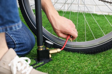 Photo of Man inflating bicycle tire with manual air pump indoors, closeup