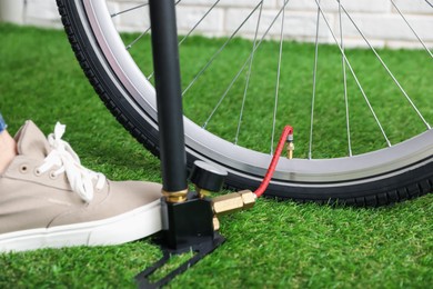 Photo of Man inflating bicycle tire with manual air pump indoors, closeup