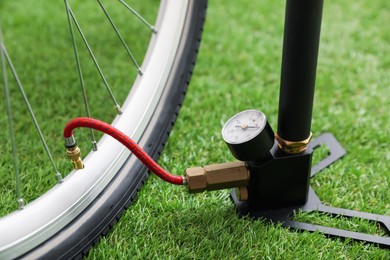 Photo of Bicycle and manual air pump on artificial grass, closeup
