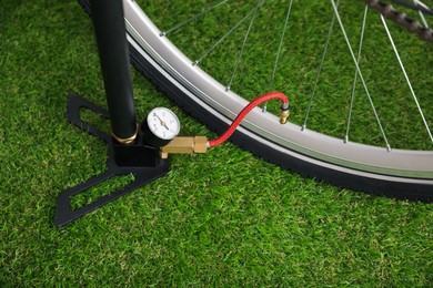 Photo of Bicycle and manual air pump on artificial grass, closeup