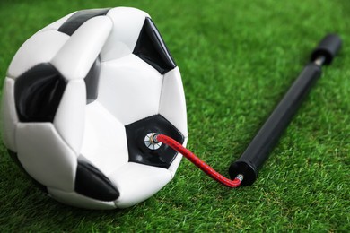Photo of Soccer ball and manual air pump on artificial grass, closeup