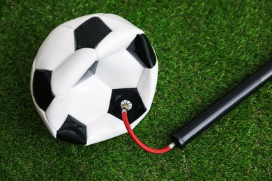 Photo of Soccer ball and manual air pump on artificial grass