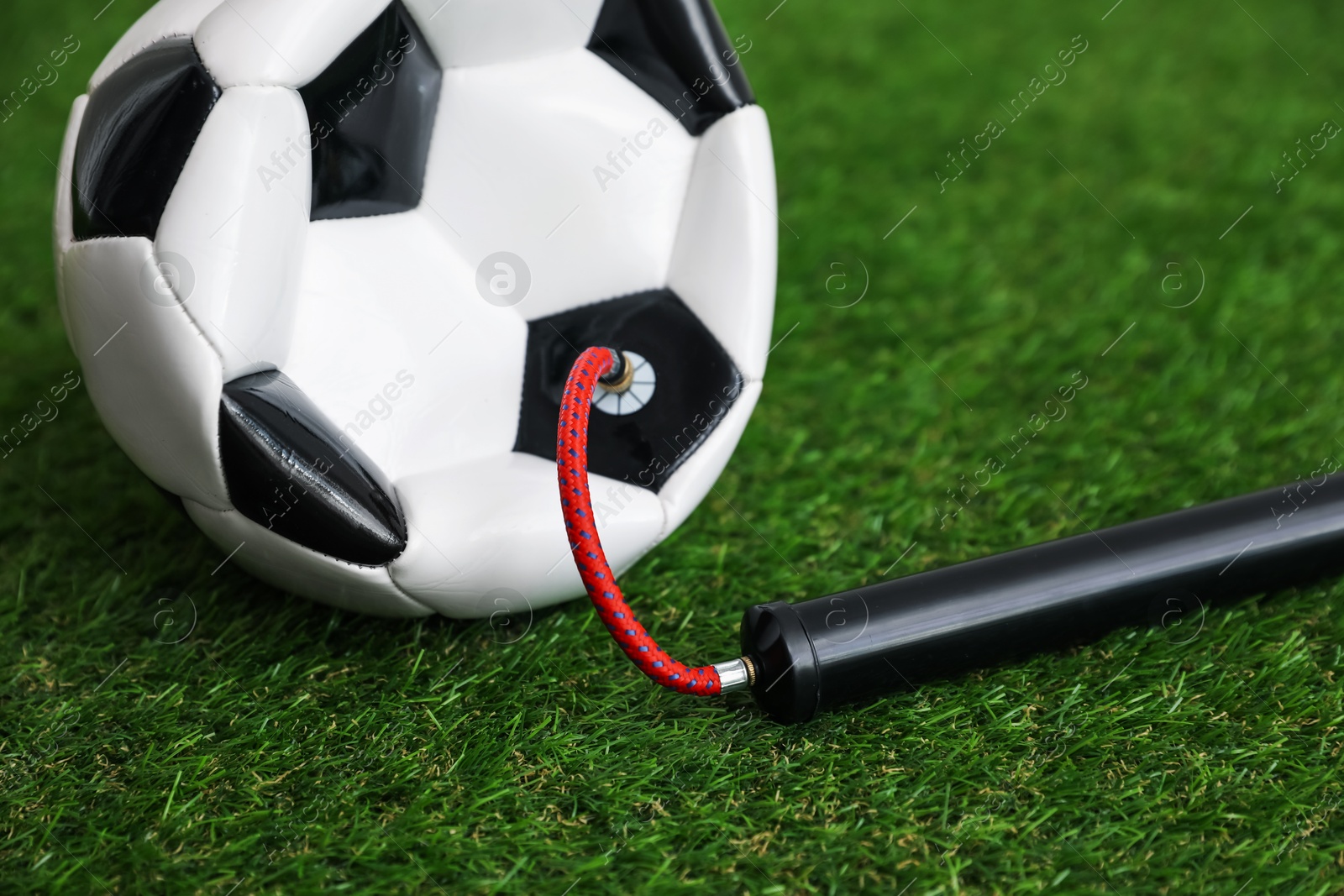 Soccer ball and manual air pump on artificial grass, closeup Photo of Soccer ball and manual air pump on artificial grass, closeup